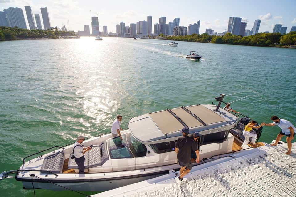People boarding a speedboat at Miami waterfront with downtown skyline, turquoise water, and cityscape