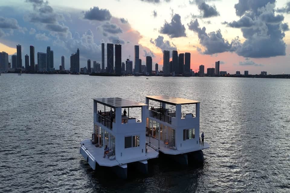 Floating luxury villa with white modern architecture overlooking Miami skyline at dusk
