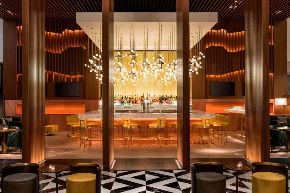 Luxury bar lounge with cascading white pendant lights, wood paneling, and modern design