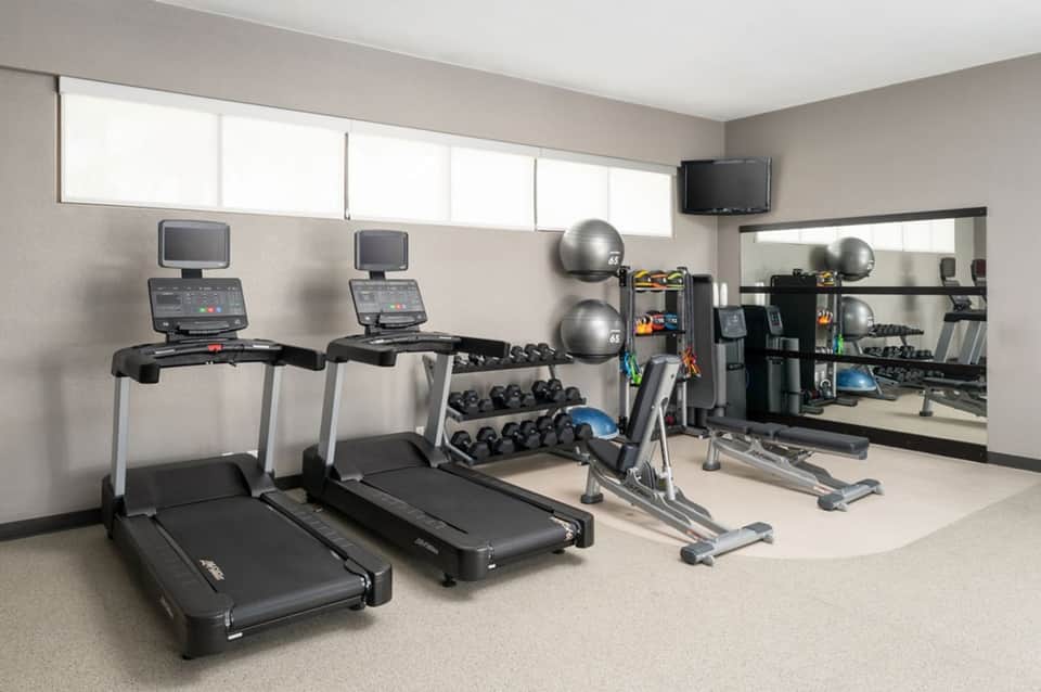 Fitness center with treadmills, dumbbells, exercise balls, and wall mirror