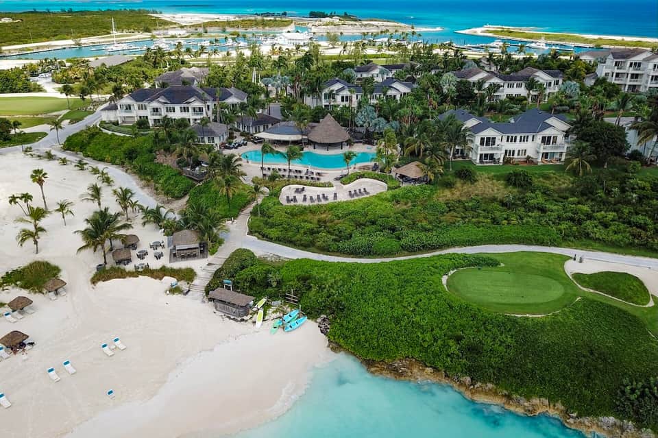 Aerial view of luxury beachfront resort with pool, homes, and turquoise ocean waters