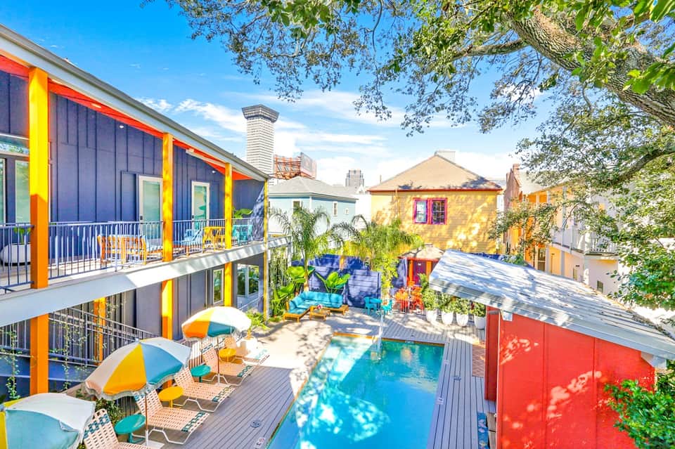Vibrant colorful hotel courtyard with bright blue and yellow architecture, small pool, and umbrellas