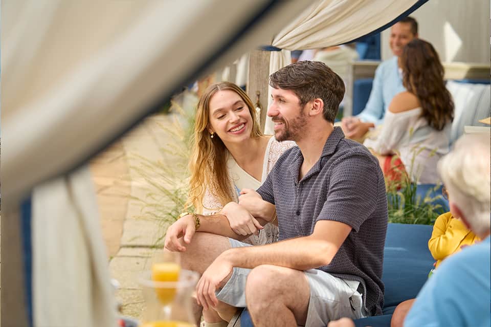 Couple relaxing together at resort lounge area with other guests in background