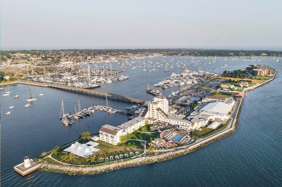 Aerial view of waterfront resort on peninsula with sailboats, docks, and surrounding harbor