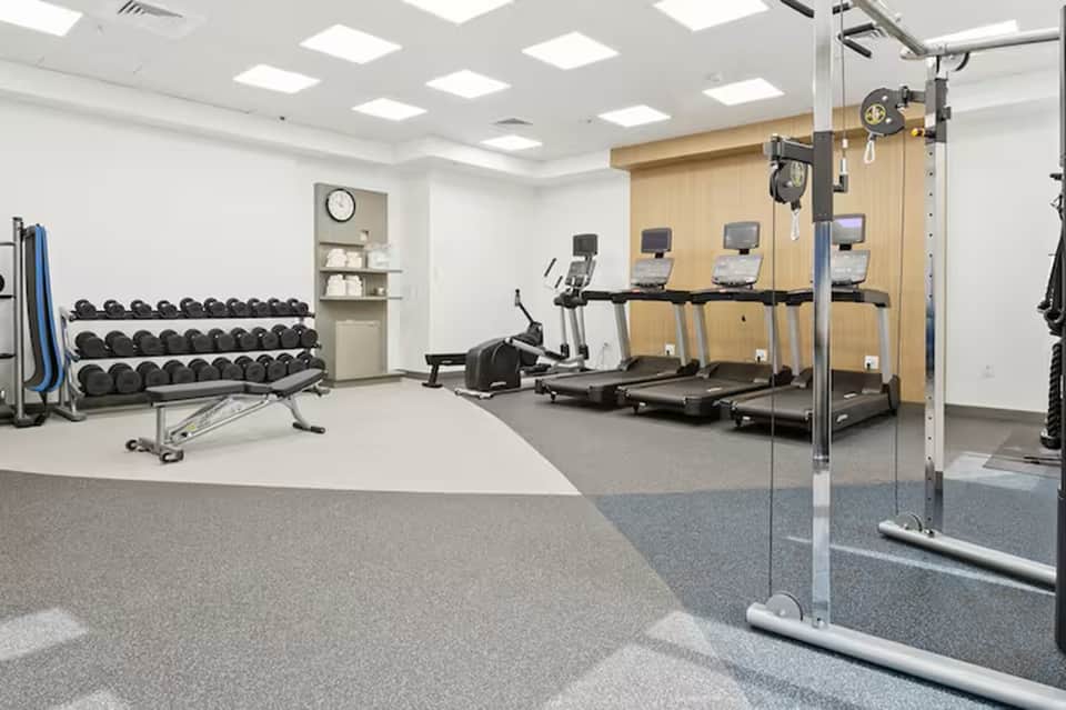 Fitness center with treadmills, dumbbells, wall mirror, and exercise equipment
