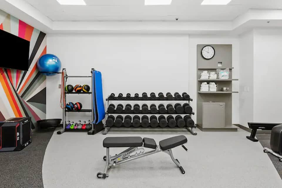 Modern hotel fitness center with dumbbells, medicine balls, gym equipment, and colorful wall art