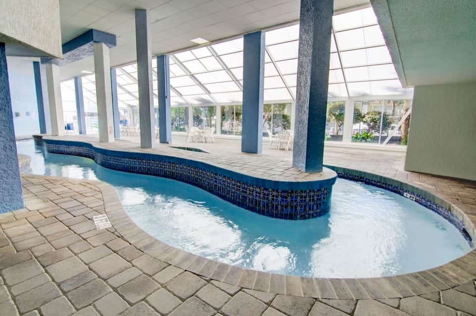 Indoor thermal pool with curved edges, blue tile accents, and skylight ceiling