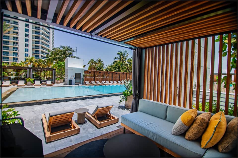Modern poolside lounge with wooden chairs, covered seating area, and resort architecture