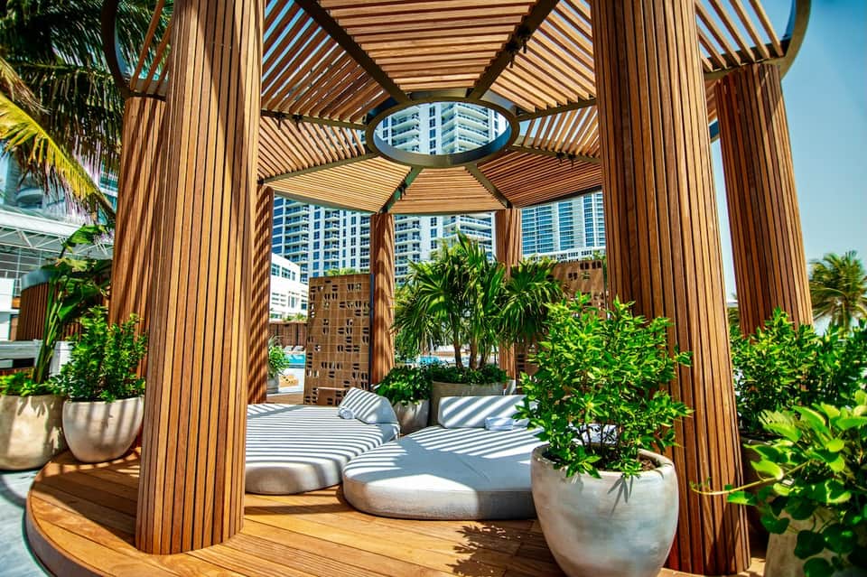 Wooden pergola lounge area with modern seating and potted plants overlooking urban landscape