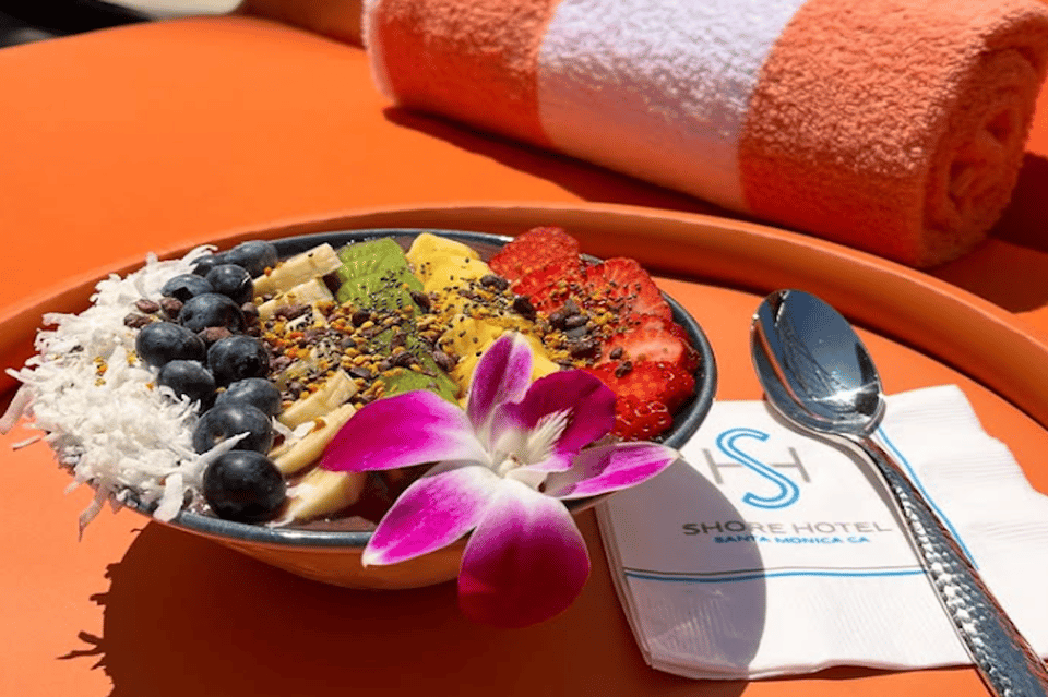 Colorful acai bowl with fresh berries and flowers at Shore Hotel with orange napkin