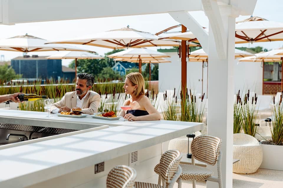 Upscale rooftop bar with couple dining under white umbrellas and pergola structure