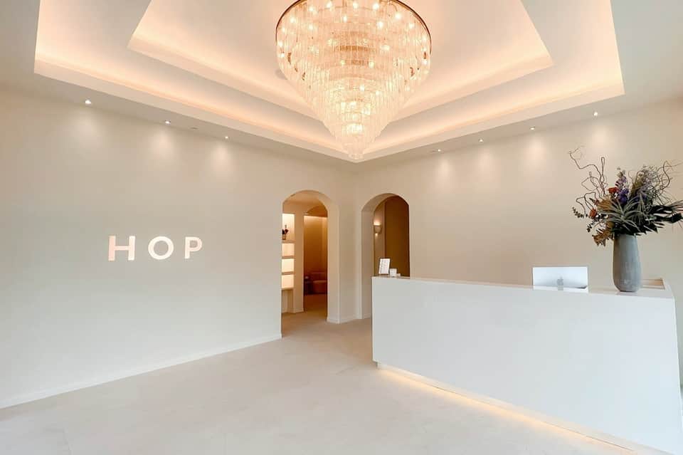 Minimalist hotel reception area with white walls, crystal chandelier, and HOP signage
