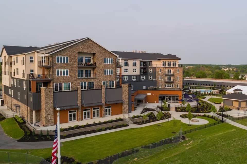 Multi-story brick and stone resort building with orange accents and manicured lawn grounds