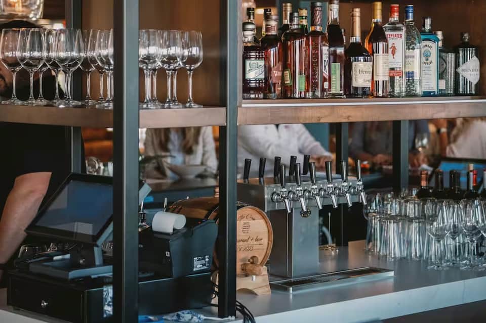 Full-service bar with shelves of liquor bottles, wine glasses, beer taps, and polished counter setup