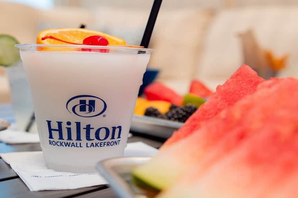 Hilton Rockwall Lakefront cocktail with fruit garnish beside plate with fresh berries