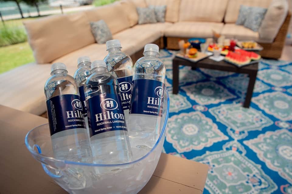 Branded water bottles on table near outdoor seating area with cushioned furniture