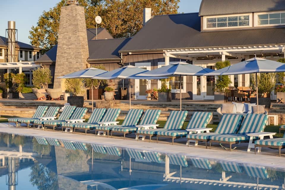 Resort pool area with striped loungers, umbrellas, and architectural complex