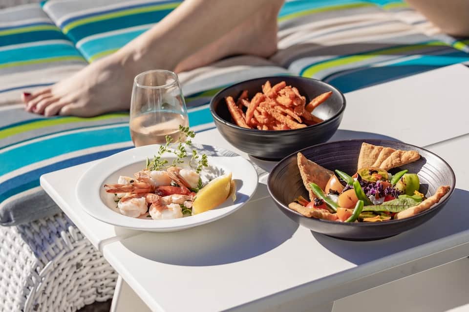 Poolside dining with gourmet seafood and appetizers on striped beach towel