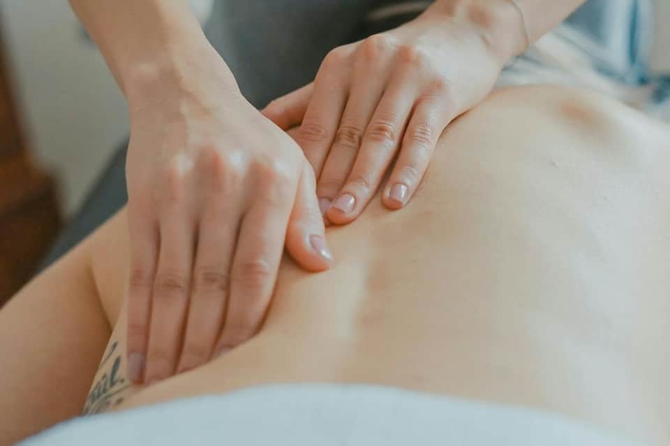 Close-up of hands receiving spa massage or wellness treatment on shoulder