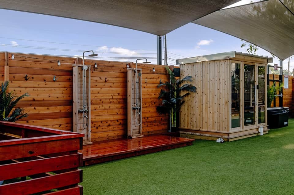 Outdoor shower and sauna facilities with wooden construction and metal shade structure