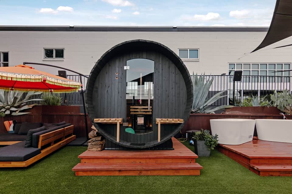 Unique barrel-shaped cabin on artificial turf surrounded by modern seating areas
