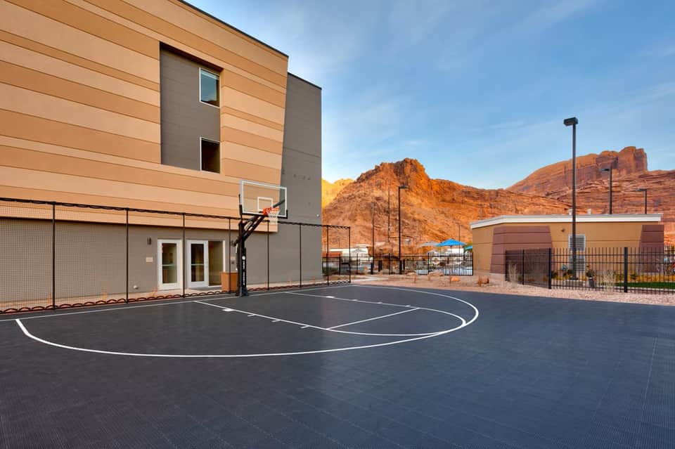 Outdoor basketball court next to modern building with desert mountains in background
