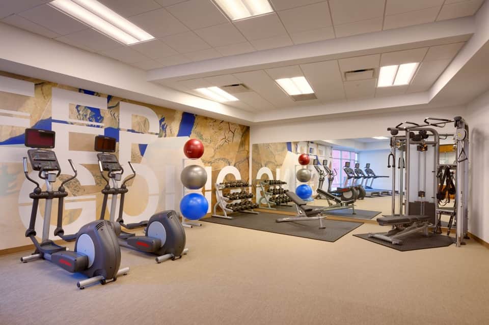 Fitness studio with cardio equipment, dumbbells, exercise balls, and motivational wall art