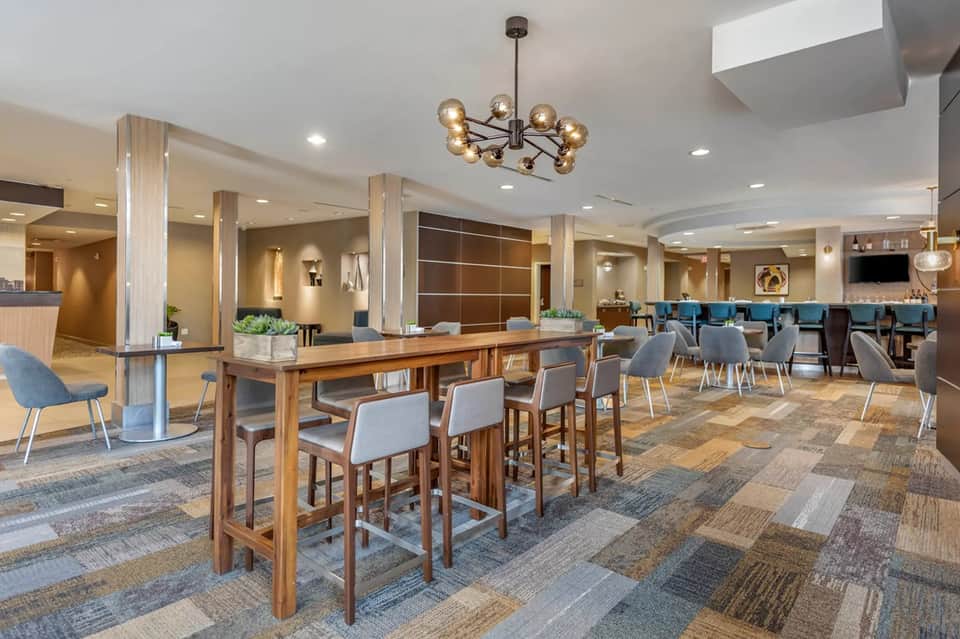 Hotel lobby and bar area with wooden pillars, patterned flooring, modern furnishings, and contemporary design