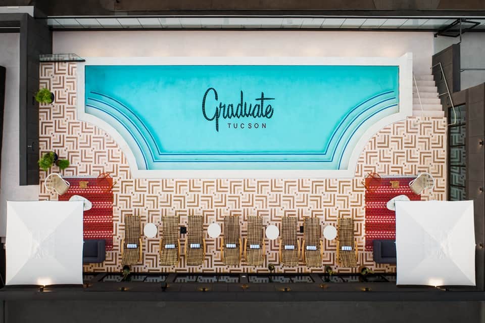 Hotel event space with turquoise ceiling signage reading 'Graduate Tucson' and geometric floor pattern