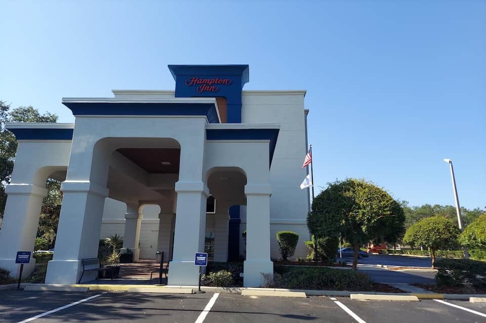 Hamilton Inn hotel exterior with white columned entrance and manicured hedges under blue sky