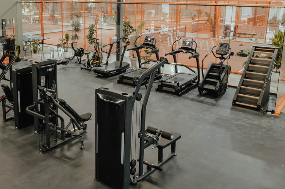 Modern fitness center with cardio equipment and floor-to-ceiling orange-framed windows