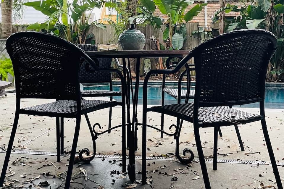 Black patio chairs and table overlooking a small residential pool area