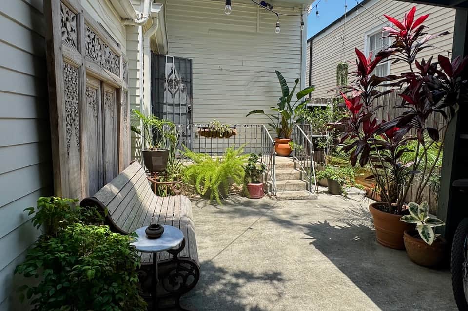 Residential patio space with tropical plants, wooden decking, and metal railings