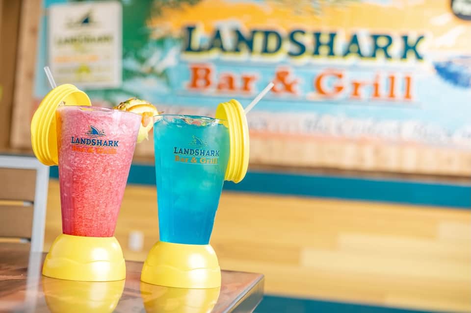 Two colorful tropical cocktails with yellow drink holders at Landshark Bar & Grill