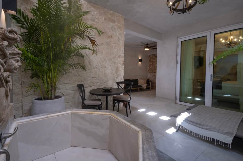 Covered patio area with soaking tub, potted plants, dining table, and ocean view doors