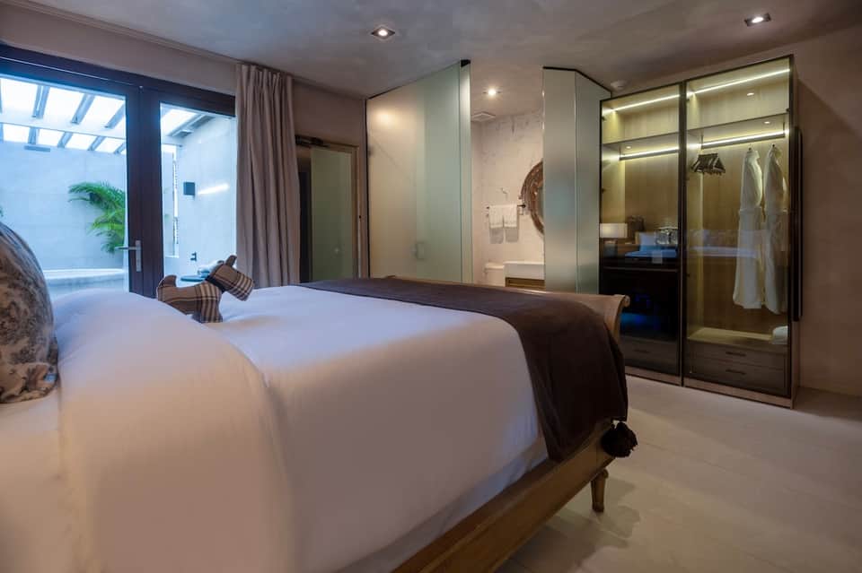 Modern hotel bedroom with king bed, ensuite bathroom, and patio access