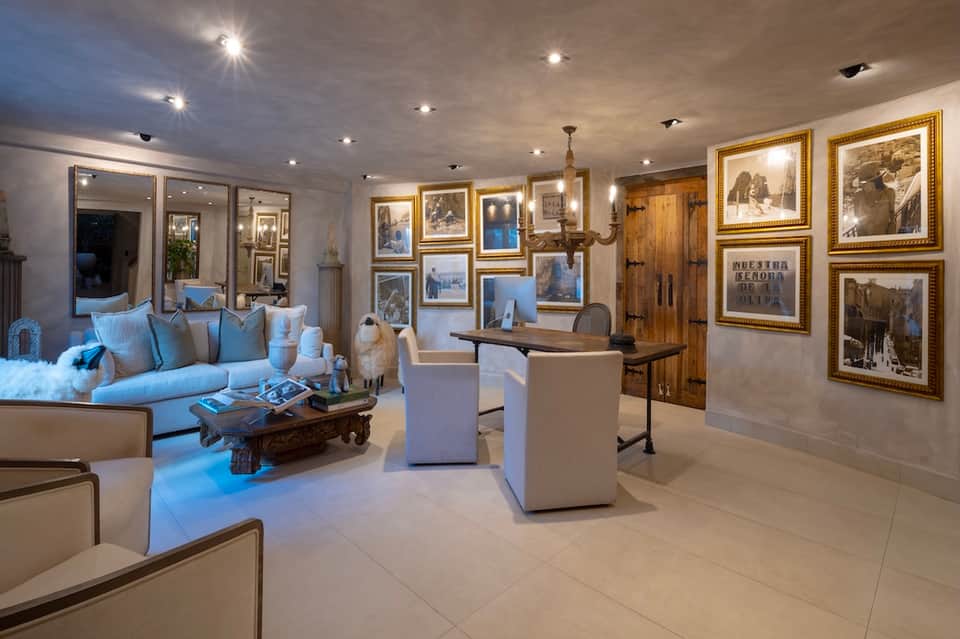 Sophisticated lounge with blue sofa, framed artwork gallery wall, mirrors, and modern furnishings
