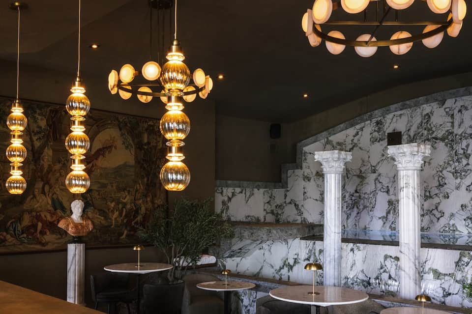 Elegant restaurant interior featuring gold sphere pendant lights and marble-pattern wall finishes