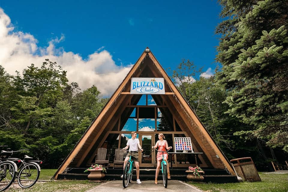 Blizzard Chalet A-frame cabin with couple on bicycles in forest setting