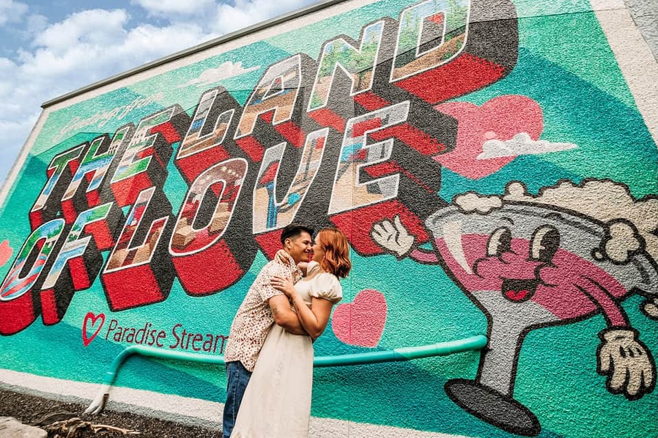 Couple posing in front of vibrant street mural with hearts and 'Love Life' text