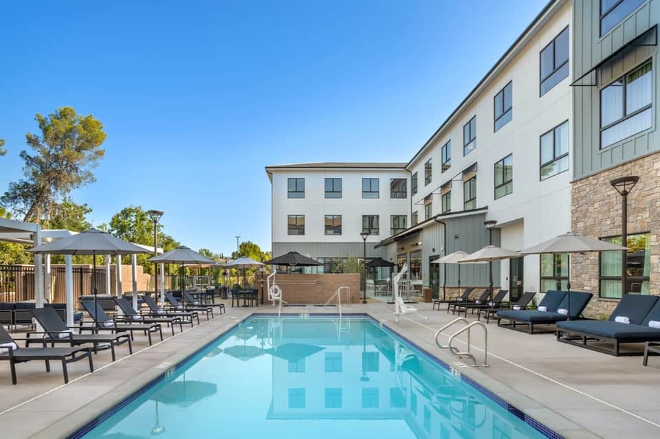 Hotel courtyard pool with lounge chairs, umbrellas, and modern building exterior