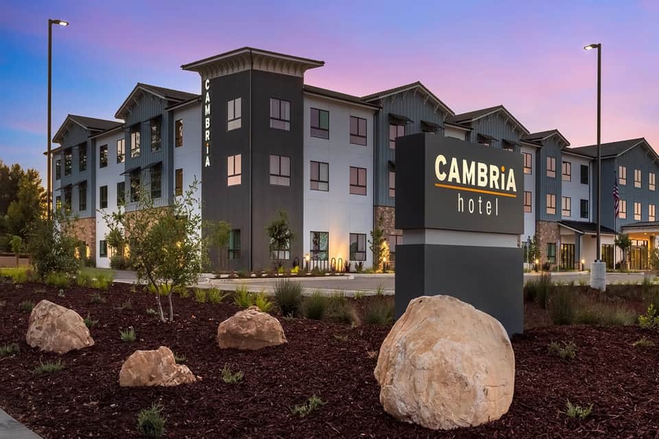 Contemporary Cambria Hotel exterior at dusk with modern architecture and decorative landscaping boulders