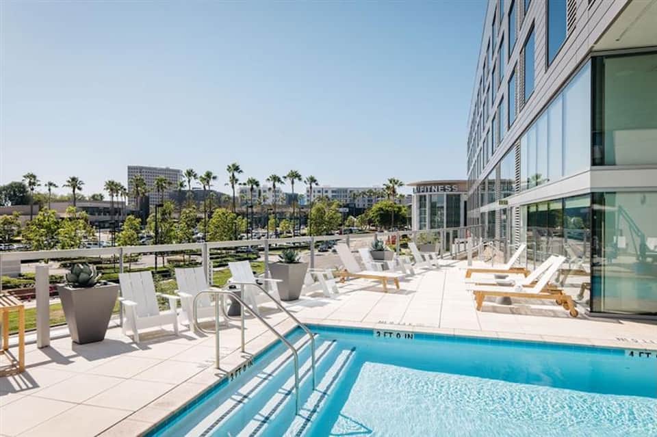 Resort pool and lounge area with white seating and palm-lined landscape views