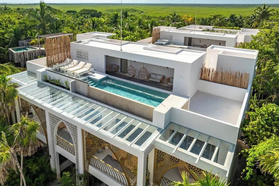 Luxury white villa with integrated pool and spa overlooking lush green landscape
