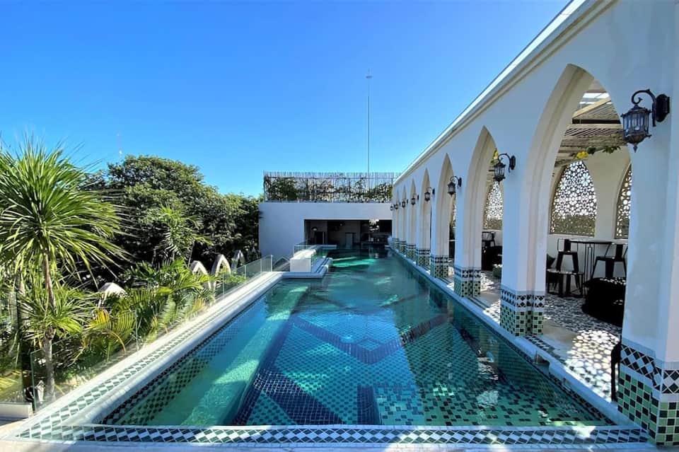 Elegant indoor lap pool with Moroccan-style white archways and decorative tile accents