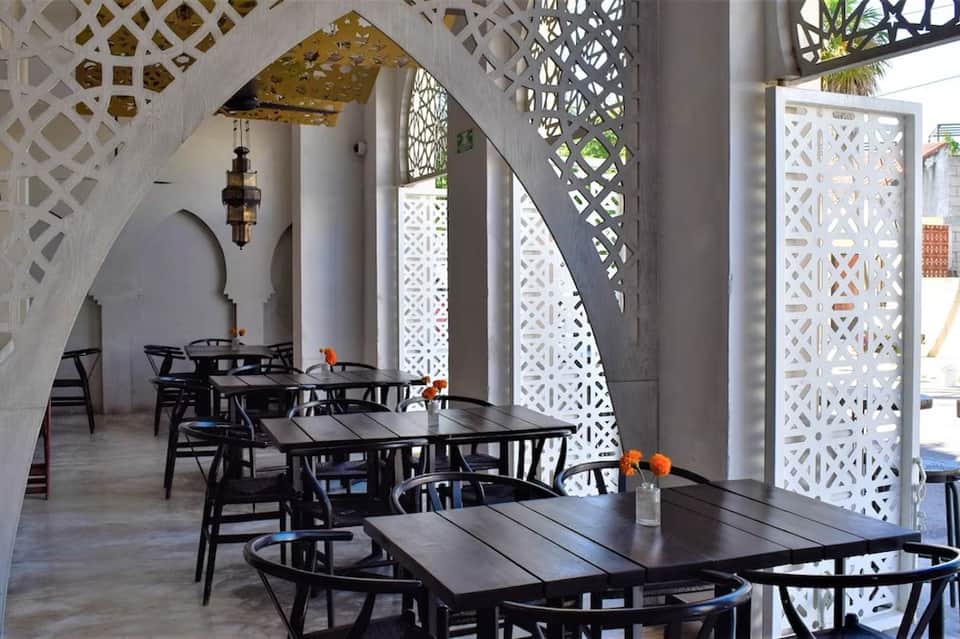Mediterranean-style restaurant with white geometric screens, black furniture, and arched architecture