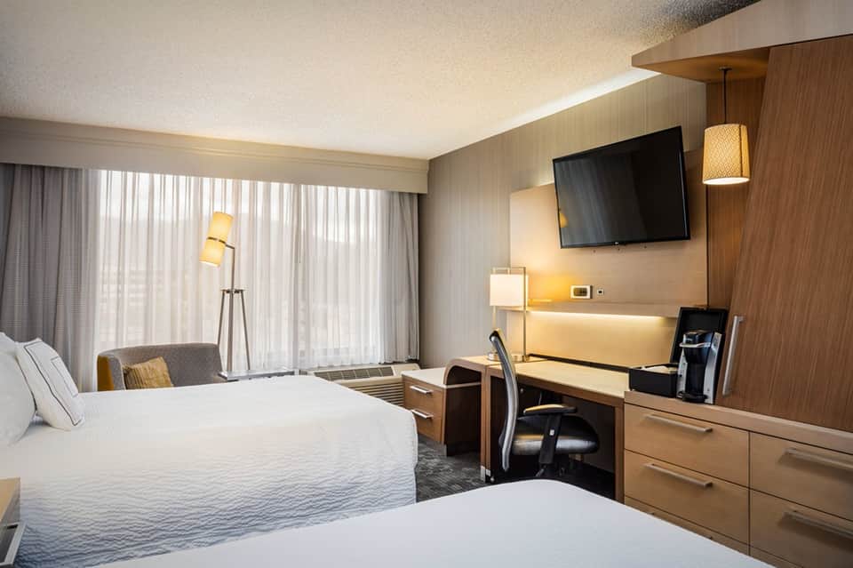 Hotel guest room with queen beds, desk, TV, and contemporary decor