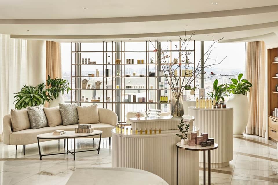 Luxury spa lounge with curved beige sofa, floor-to-ceiling windows, and city skyline