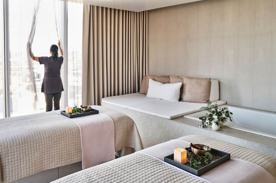 Spacious hotel room with two beds, ocean view windows, and modern furnishings