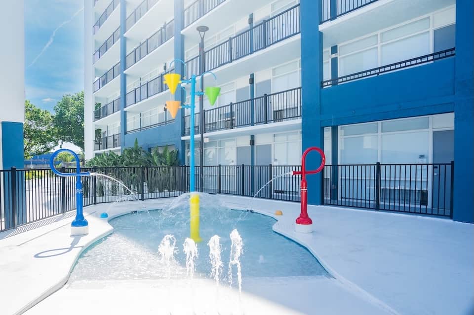 Splash pad play area with colorful water features in modern resort courtyard